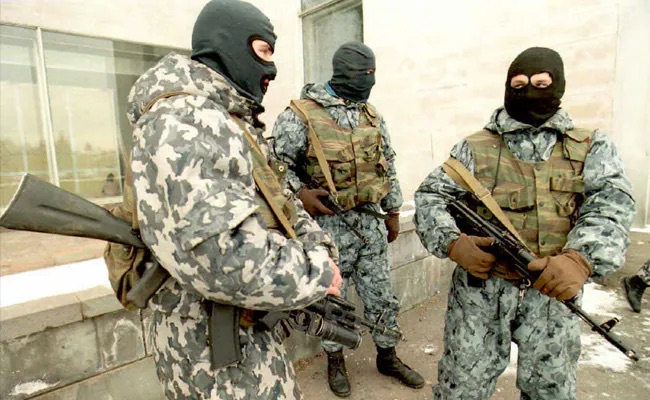 A prepared specialist team assembled in a cold urban environment, equipment checked before a planned movement.